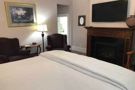 white bed with chairs and fireplace